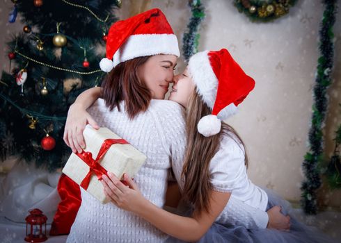 Mother and daughter hugging under Christmas tree nose-to-nose