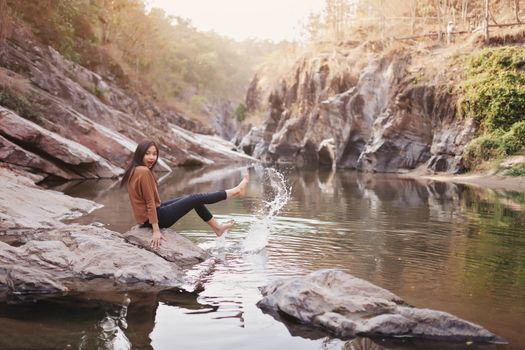 Young woman on a river bank playing with water.