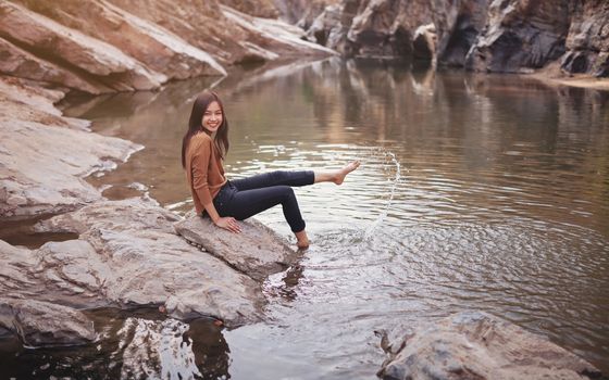 Young woman on a river bank playing with water.
