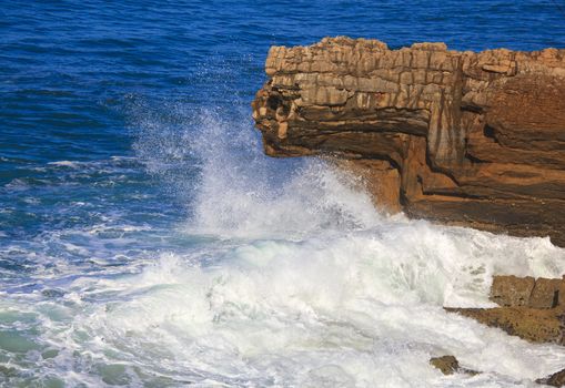 Marine wave breaks against offshore stone