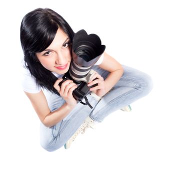 black haired girl sitting on the floor, holding a professional dslr camera, looking up