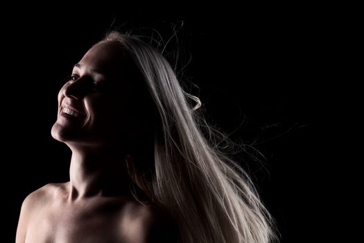 portrait of a blond girl with windy hair, on black background