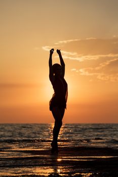 Silhouette of a girl dancing on the background of sea sunset