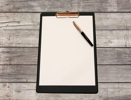 A white sheet of paper with pen on a wooden table made of grey Board
