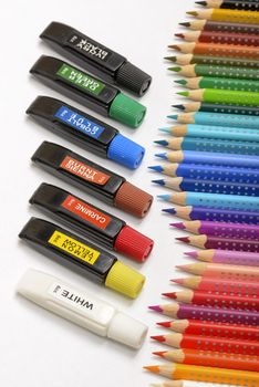 Bundle of colored pencils and tubes of paint on the colorful background