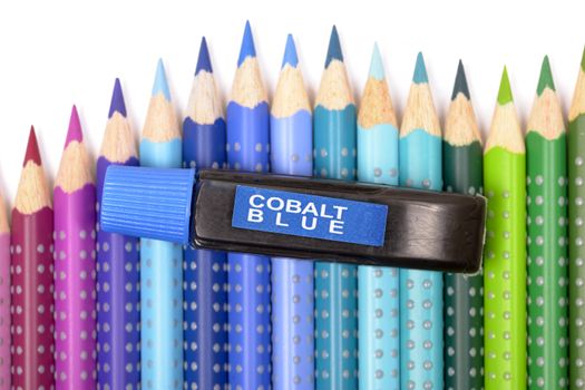 Bundle of colored pencils and tubes of paint on the colorful background