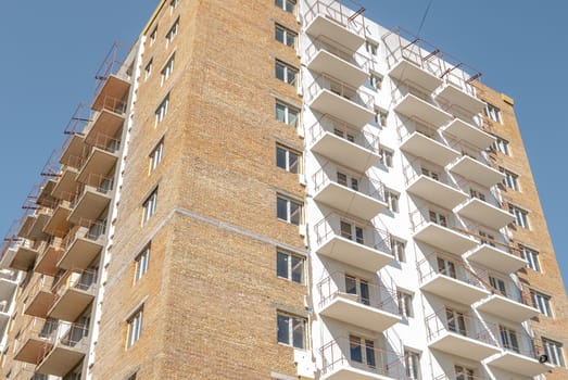 kind of a new multistorey brick residential building with balconies on a sunny day