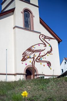 Stylized stork with easter eggs, in the background a church
