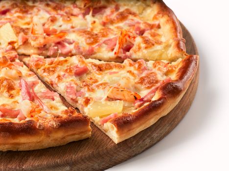 Close up view on piece of pizza with ham and pineapple on wooden cutting board. Isolated on white with clipping path