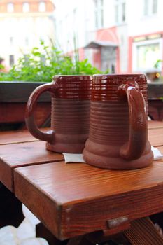 Two traditional clay beeg mugs on wooden table in cafe