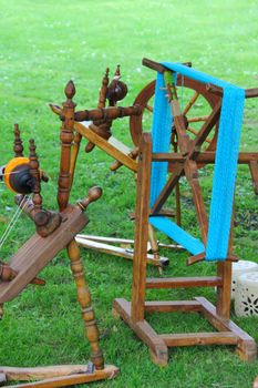 Old traditional wooden spinning wheel on grass at fair