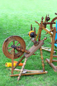 Old traditional wooden spinning wheel on grass at fair