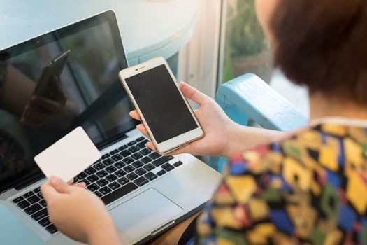 Woman holding smartphone and credit card for online shopping payment. E-commerce using internet and mobile application concept