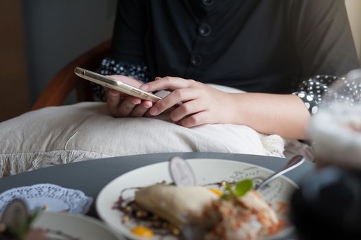 Woman hand using smartphone for social media in coffee shop on weekend. Vacation lifestyle in cafe