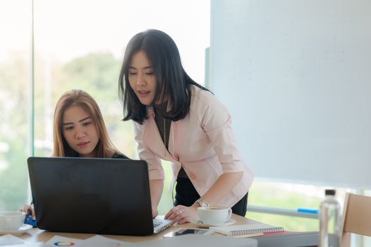 Young Asian business workers working together with laptop computer in office. Business startup teamwork and brainstorm concept