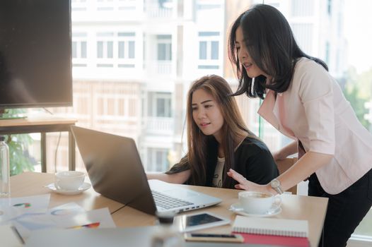 Young Asian business workers working together with laptop computer in office. Business startup teamwork and brainstorm concept