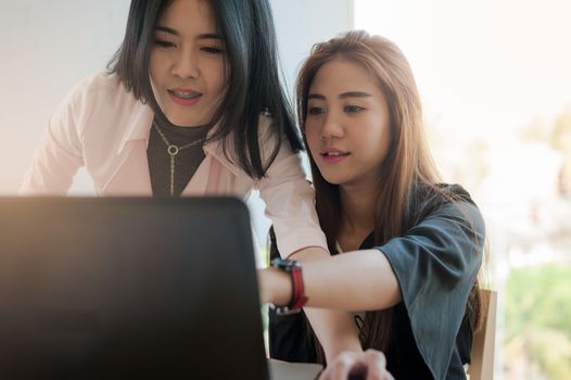 Young Asian business workers working together with laptop computer in office. Business startup teamwork and brainstorm concept