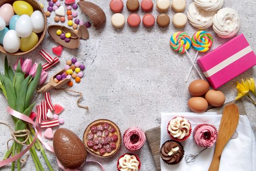 Selection of easter sweets, bakery cupcakes, chocolate eggs and confectionery with copy space in the middle