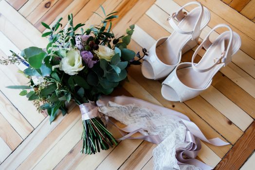 Bride's shoes and a bridal bouquet on the parquet