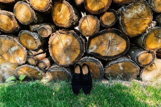 Groom shoes on the grass under a pile of logs