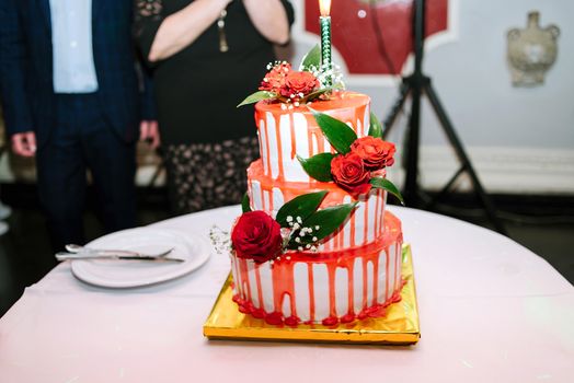 White wedding three-tiered cake with red glaze and roses