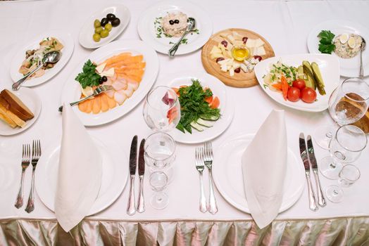 Dinner table with different dishes and empty cutlery. Table setting