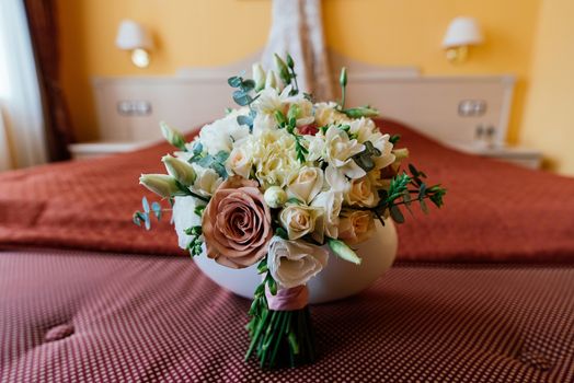 Beautiful lush wedding bouquet on a bed in a bride's bedroom 