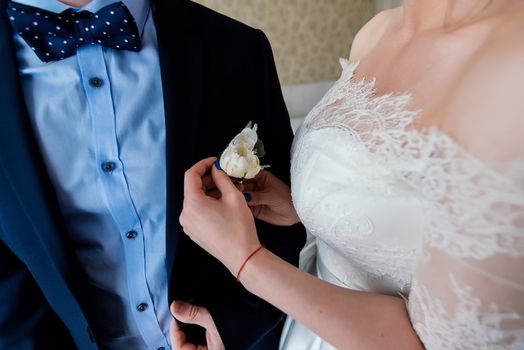 Bride fastens groom boutonniere to buttonhole