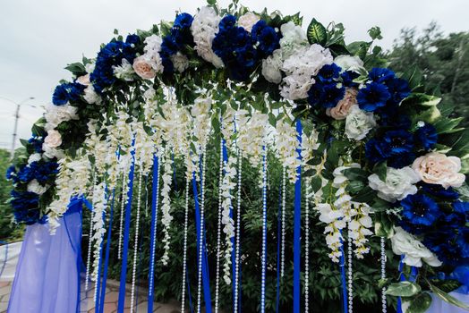 Wedding arch with blue, white flowers, greenery and blue ribbons