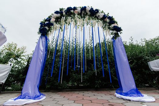 Wedding arch with blue, white flowers, greenery and blue ribbons