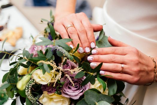 Beautiful bride's manicure over a wedding bouquet