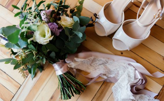 Bride's shoes and a bridal bouquet on the parquet