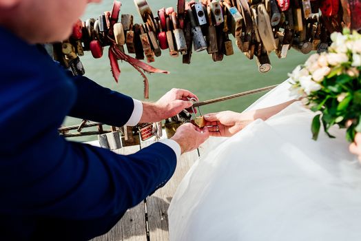 Gold wedding lock in the form of heart in the hands of the bride and groom. 