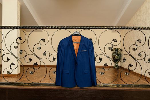 Beautiful blue groom's jacket hanging on the wrought-iron railing