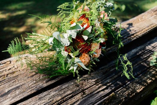 Lush wedding bouquet on a gray wooden bench near the water 