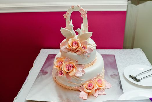White two-tier wedding cake with roses and two pigeons