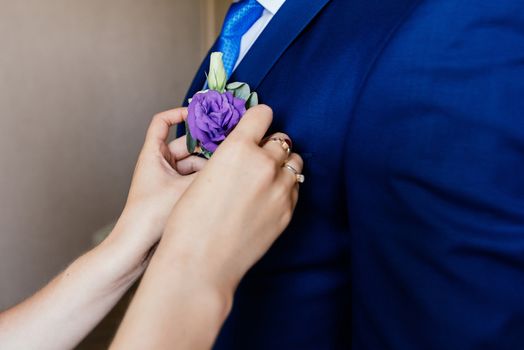 Woman inserting the boutonniere in buttonhole of man in suit