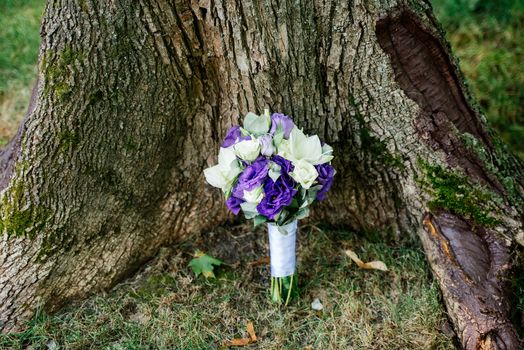 Wedding bouquet of white and purple flowers under the tree