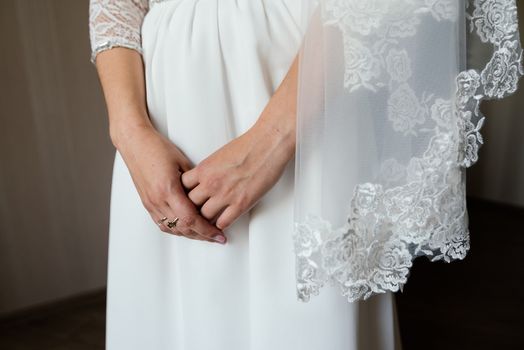 Bride's hands crossed on white dress