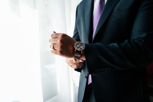 Watch on the wrist of a man in black suit.
