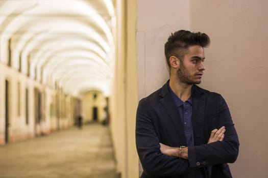 Handsome young man under cloisters in Italian city center, Turin, at night
