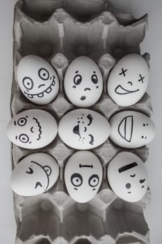 Eggs with faces photo for your design. in the box. Funny and cute. Nine in the shape of a square of happiness in the middle