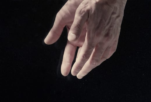 Man's hands under water on black background