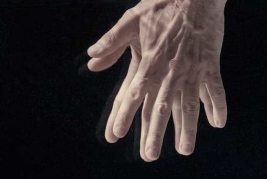 Man's hands under water on black background