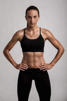 Portrait of sporty young woman with muscular body looking at camera