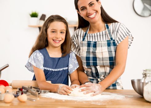 Shot of a mother and daughter having fun in the kitchen and learning to make a cake