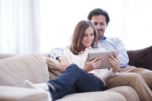 Cheerful couple using digital tablet at home