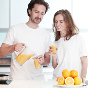 Couple with orange juice in the kitchen