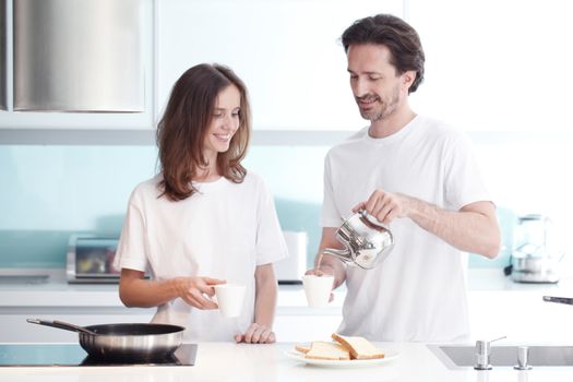 Happy couple cooking breakfast together in the kitchen