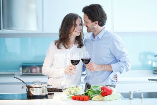 Portrait of a couple having a glass of red wine while cooking dinner